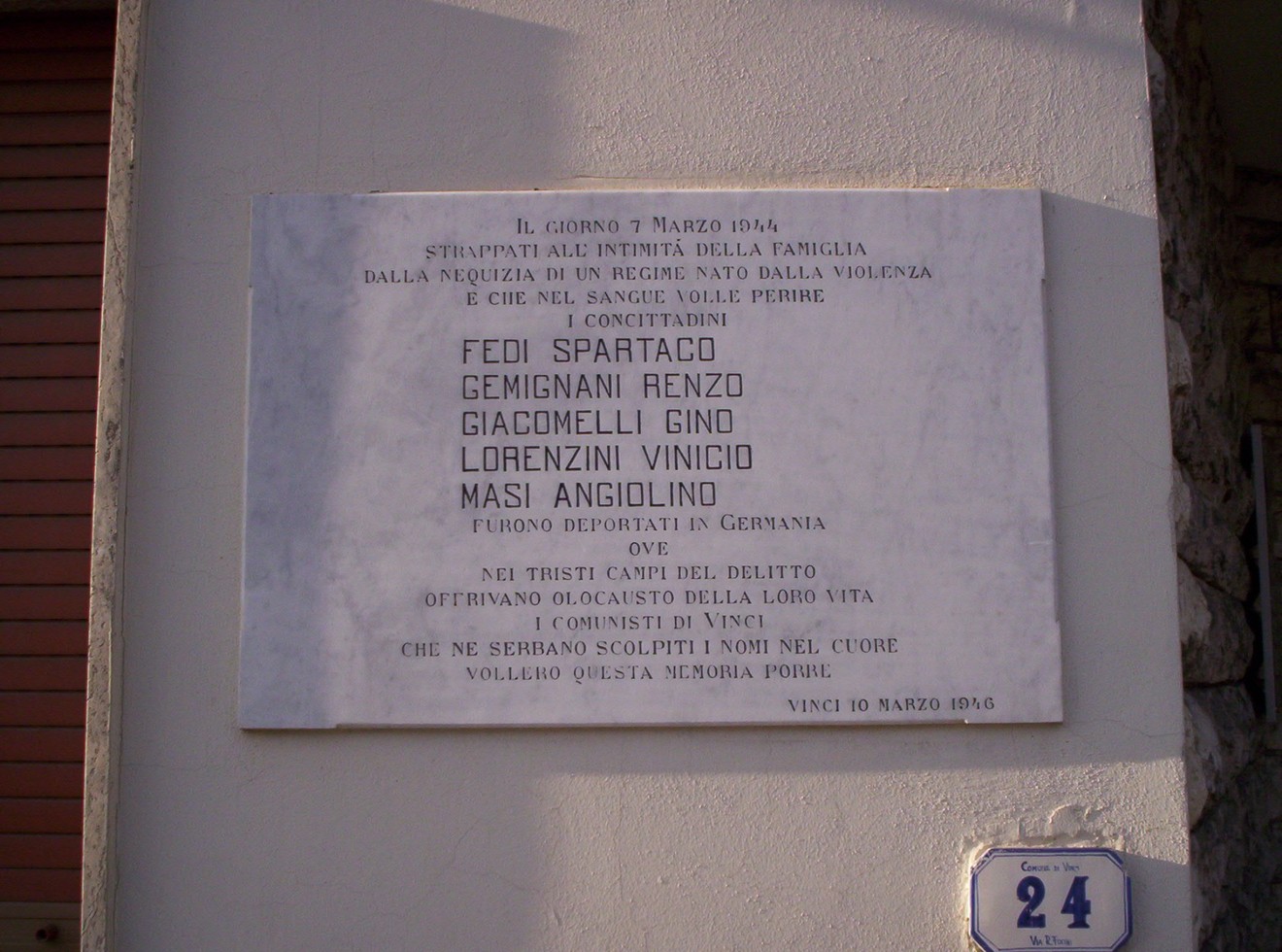 Lapide commemorativa dedicata ai deportati, con nomi e date significative del tragico evento storico.