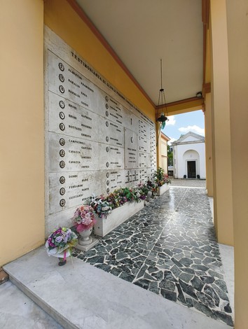 Sacrario dei Caduti Partigiani, con monumento e fiori commemorativi in un ambiente sobrio e rispettoso.