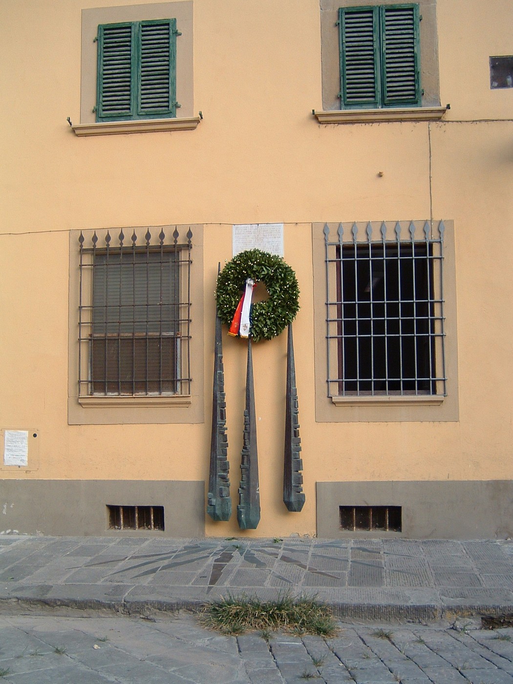 Monumento a Barducci con ghirlanda, situato su una parete di edificio storico, simbolo di commemorazione.