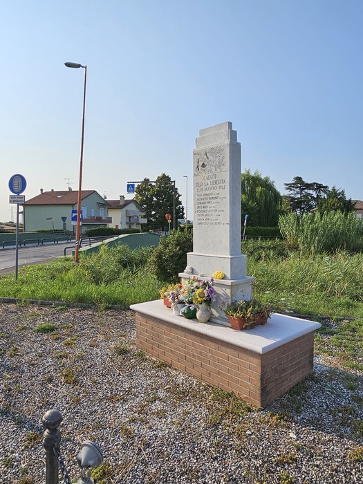 Monumento ai Martiri di Ponte Ruffio, circondato da fiori, in una zona verde e tranquilla.