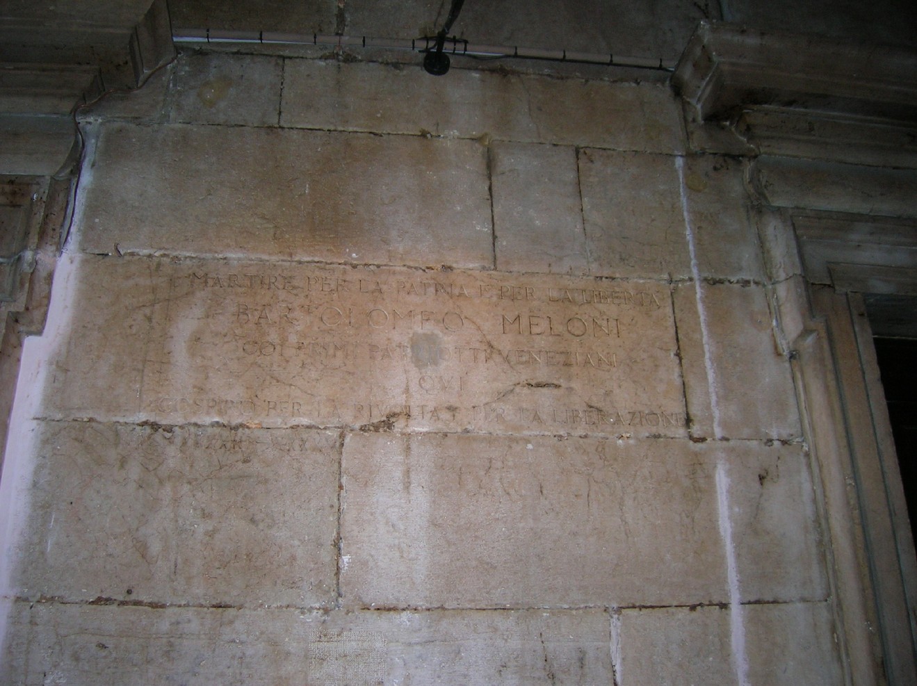 Iscrizione su una parete che celebra la memoria di un soggetto legato a Meloni.