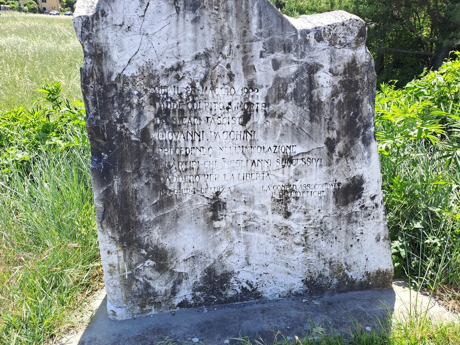 Cippo commemorativo a Pacchini, con iscrizioni che ricordano eventi storici e personaggi locali.