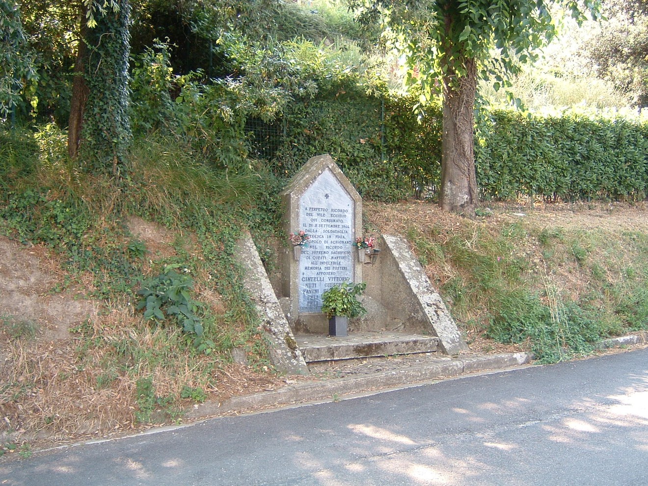 Monumento di Schignano, un tributo storico immerso nella natura, con dettagli architettonici rustici e una pianta ornamentale.