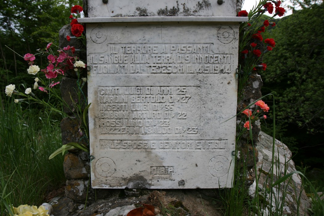 Monumento commemorativo ai caduti Manfroni e Savini, adornato da fiori e testimonianze di memoria.
