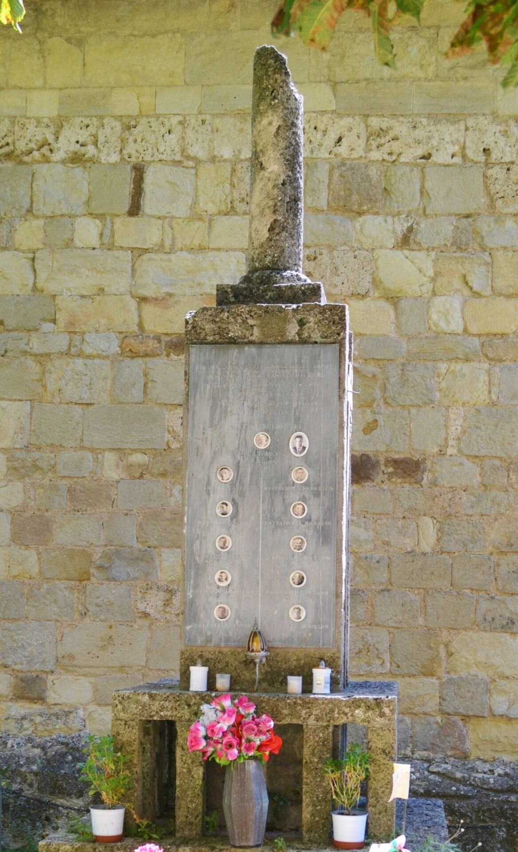 Cippo commemorativo ai Martiri di Renno, situato a Pavullo, con simboli e decorazioni floreali.