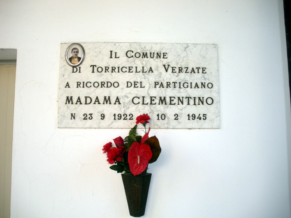 Lapide commemorativa a Madama Clementino, partigiano, a Torricella Verzate. Fiori e dedica in memoria.