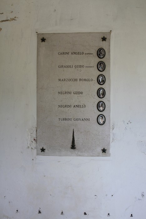 Sacrario ai Caduti Partigiani di Piumazzo con un elenco di nomi su una tavola commemorativa.