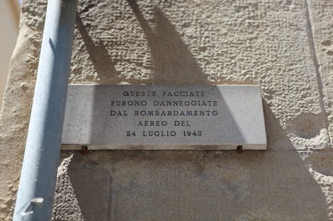 Lapide commemorativa che ricorda i danni subiti dalle facciate nel bombardamento del 24 luglio 1943.
