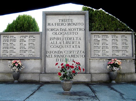 Monumento commemorativo dedicato ai caduti, con iscrizioni e fiori, simbolo di ricordo e libertà.