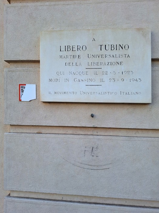 Lapide dedicata a Libero Tubino, martire universalista della liberazione, situata su un muro di pietra.