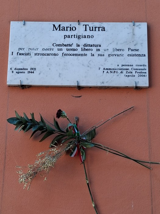 Lapide commemorativa di Mario Turra, partigiano, con fiori in omaggio. Riconoscimento della sua lotta per la libertà.