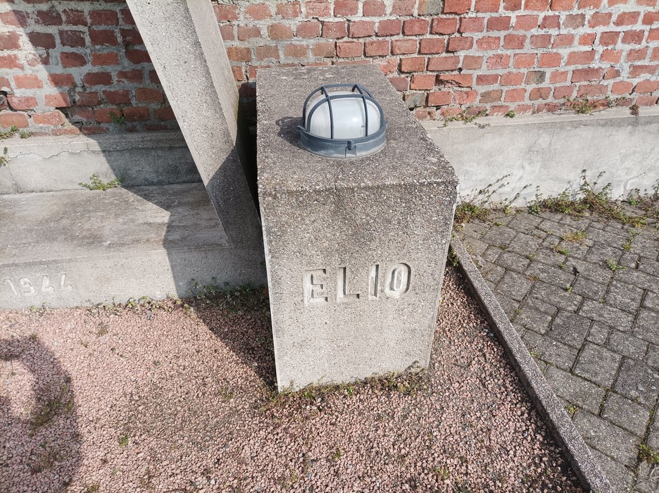 Monumento a Clerici e Zampiero con base in pietra e luce in cima. Ambientazione esterna con elementi di mattoni.