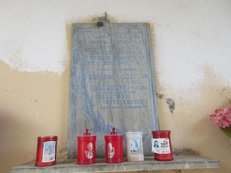 Lapide commemorativa dedicata a Bonino e Coda, con candele rosse posizionate in primo piano.