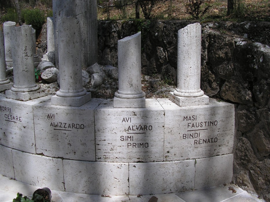 Monumento ai caduti di Scalvaia con colonne e cippi commemorativi in un contesto naturale.