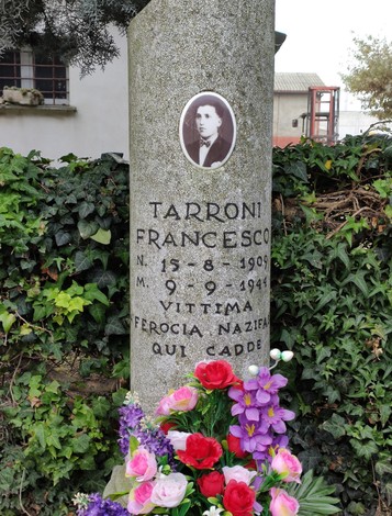 Cippo commemorativo per Tarroni Francesco, vittima della ferocia nazista, con foto e fiori decorativi.