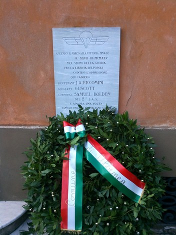 Lapide commemorativa per Riccomini, Guscott e Bolden, con corona di fiori e scritte in onore dei caduti.