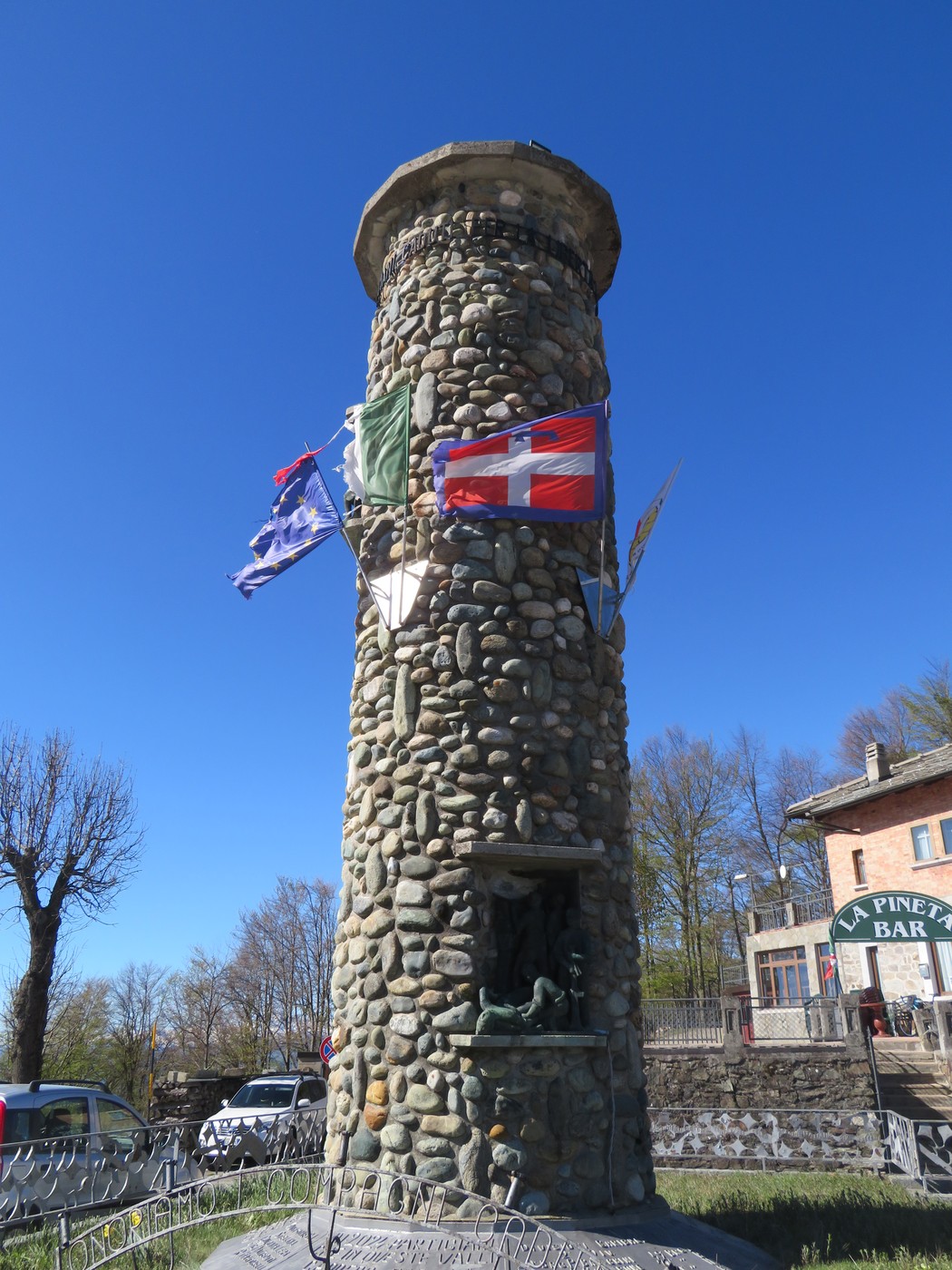 Monumento commemorativo che celebra le brigate partigiane, con una struttura in pietra e bandiere tricolori.