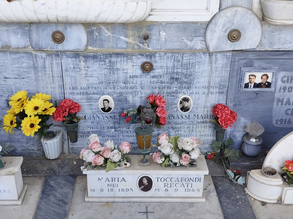 Loculi cimiteriali in marmo con foto, iscrizioni e fiori deposti davanti alle lapidi dei partigiani.