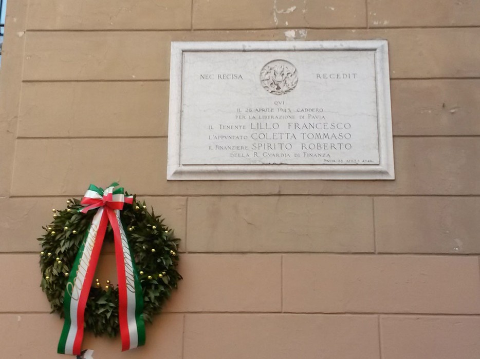 Lapide commemorativa dedicata a Lillo, Coletta e Spirito, affissa a un muro con una corona d'alloro.