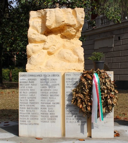 Monumento commemorativo ai caduti di Cornigliano, con una struttura in pietra e omaggi floreali.