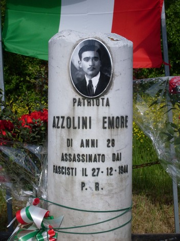 Cippo commemorativo di Emore Azzolini, assassinato dai fascisti nel 1944, decorato con fiori e bandiere italiane.