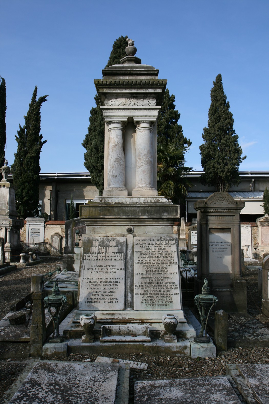 Sepolcro di Treves, monumento funerario circondato da cipressi nel cimitero, con dettagli architettonici eleganti.