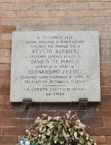Lapide commemorativa in onore di Attilio Barbieri, Danilo De Marchi e Bernardino Zelioli, con fiori allogati.