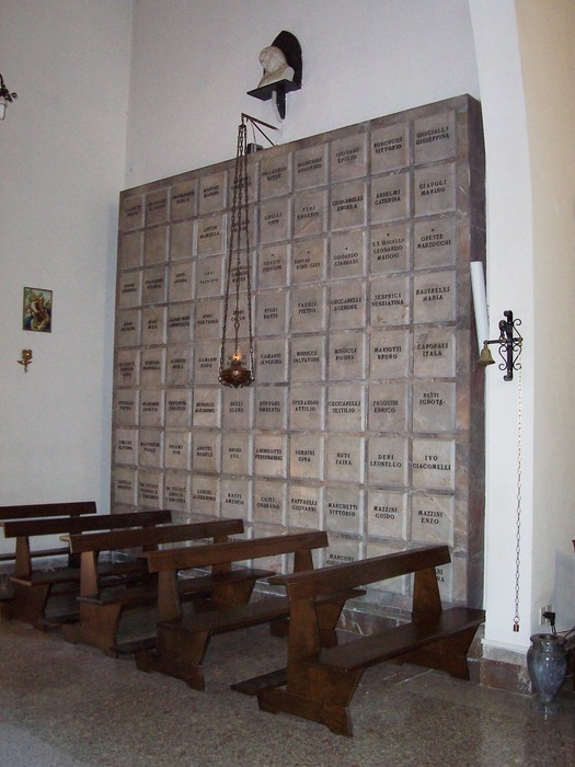 Cappella dei caduti, luogo di memoria con loculi commemorativi e semplici panche in un'atmosfera di riflessione.