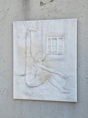 Monumento alla Resistenza, scultura in rilievo di figura umana in pose evocative, su fondo neutro.