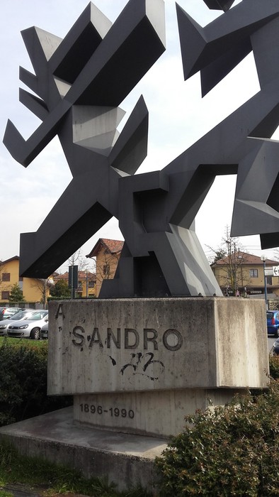 Monumento a Pertini con una struttura moderna e geometrica, circondato da verde e aree urbane.
