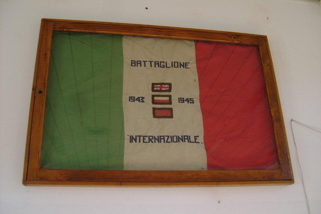 Busto a Lett, con una bandiera italiana e scritte storiche del Battaglione Internazionale 1943-1945.