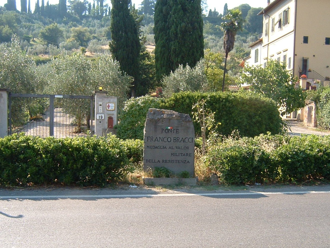 Cippo commemorativo dedicato a Franco Bracci, situato presso il ponte omonimo, circondato da vegetazione.