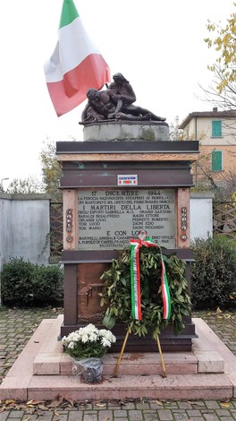 Monumento ai Martiri del Panaro, con bandiera italiana, decorazioni floreali e iscrizioni commemorative.