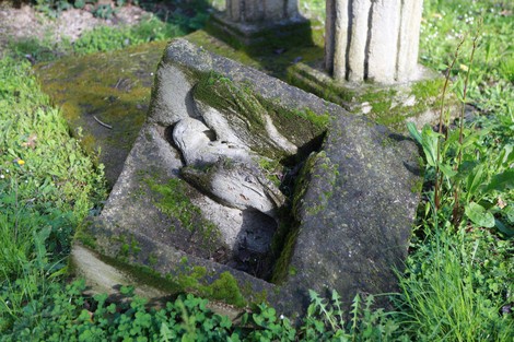 Monumento alla Resistenza circondato da erba verde e muschio, con una scultura in pietra incisiva e dettagliata.