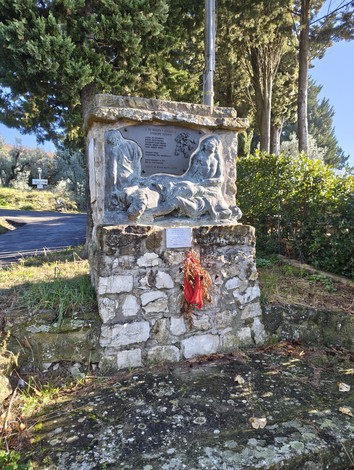 Monumento di Lonchio, con rilievi artistici e decorazioni floreali, immerso nella vegetazione.