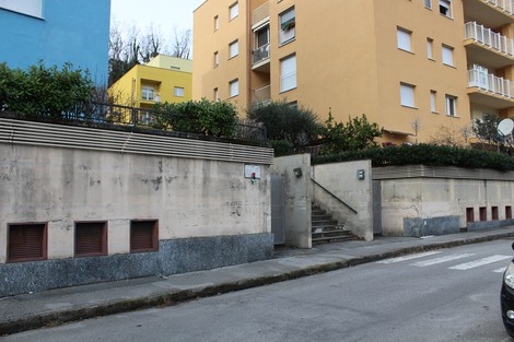 Lapide situata a Frassinello, visibile in un contesto urbano con muri e edifici colorati.