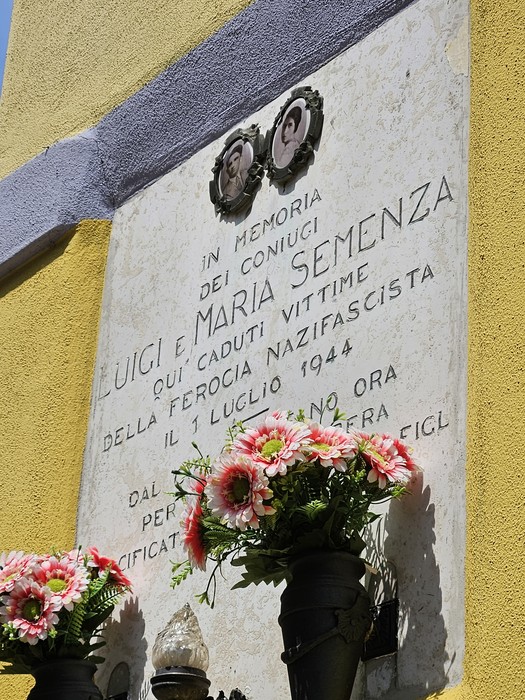 Lapide commemorativa dedicata ai coniugi Semenza, con fiori decorativi e una sobria cornice storica.