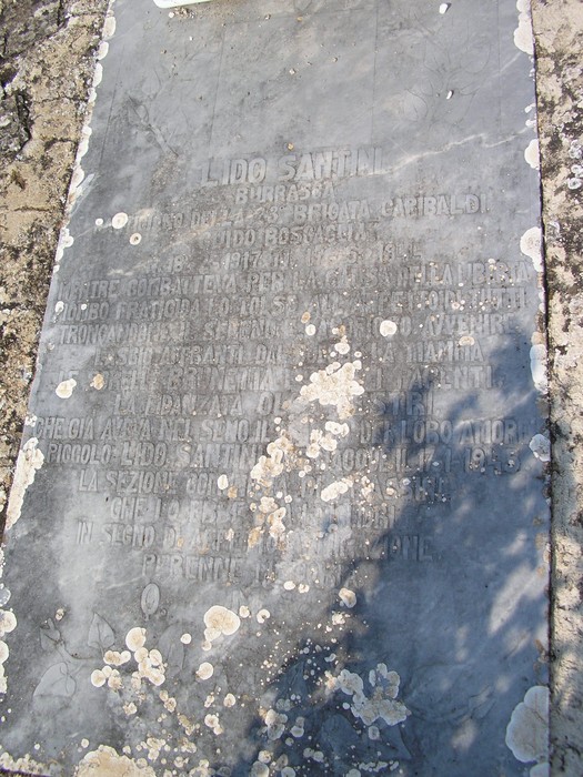 Sepolcro di Lido Santini, monumento commemorativo con iscrizioni storiche, situato in un contesto naturale.