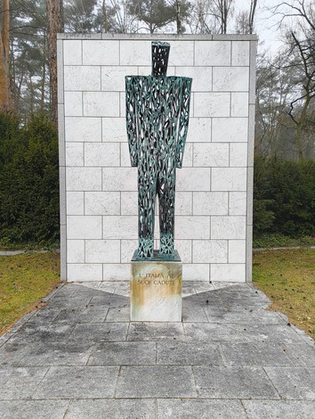 Monumento al Cimitero militare italiano di Zehlendorf, rappresentante una figura stilizzata in metallo circondata da natura.