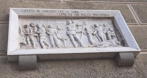 Lapide alla Libertà, decorata con figure simboliche e un messaggio di lotta per la libertà.
