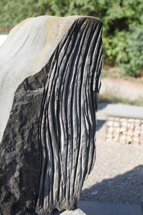 Dettaglio di un monumento in pietra con superfici incise, protagonista di un memoriale commemorativo.