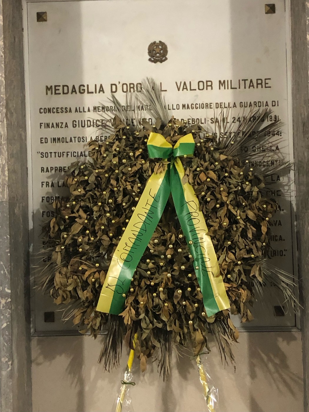 Lapide commemorativa con corona d'alloro dedicata al Giudice, in onore del suo valor militare.