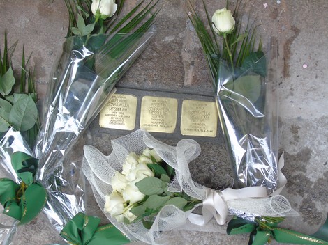 Pietre d'inciampo dedicate alla famiglia Scaramella Messulam, circondate da fiori bianchi e decorazioni.