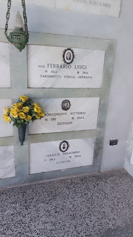 Cappella ai caduti di Brugherio con lapidi commemorative e un mazzo di fiori gialli.