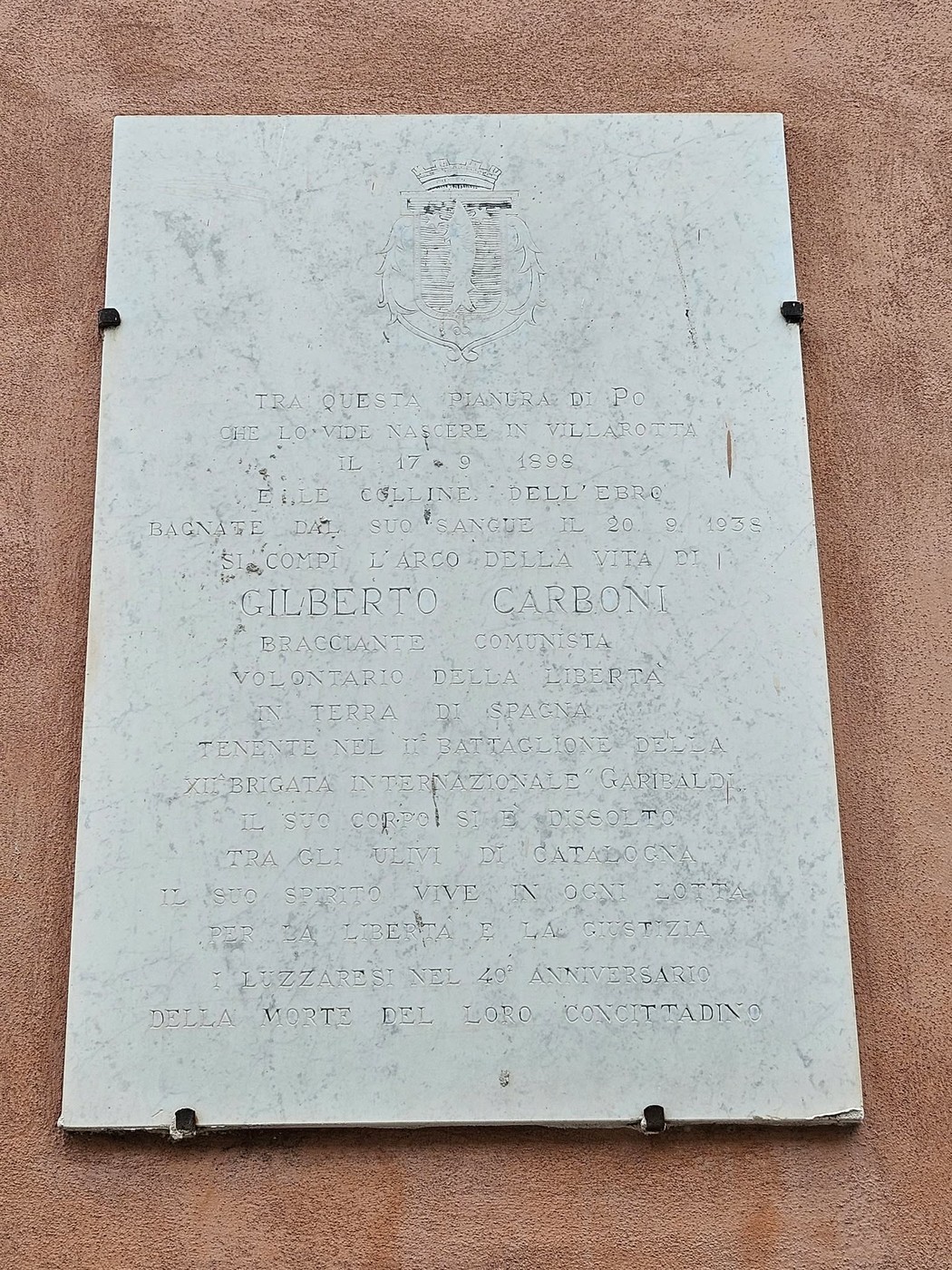 Lapide commemorativa dedicata a Gilberto Carboni, con iscrizioni su vita e opera, situata su edificio storico.