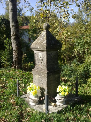 Cippo in pietra circondato da fiori, immerso nel verde, rappresenta un memoriale a Torri e Bragazzi.