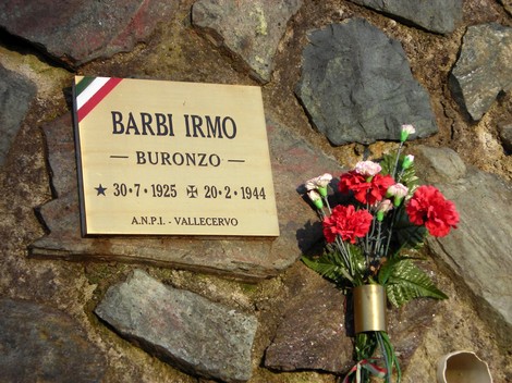 Targa commemorativa dedicata a Irmo Barbi, situata a Buronzo, con fiori accanto.