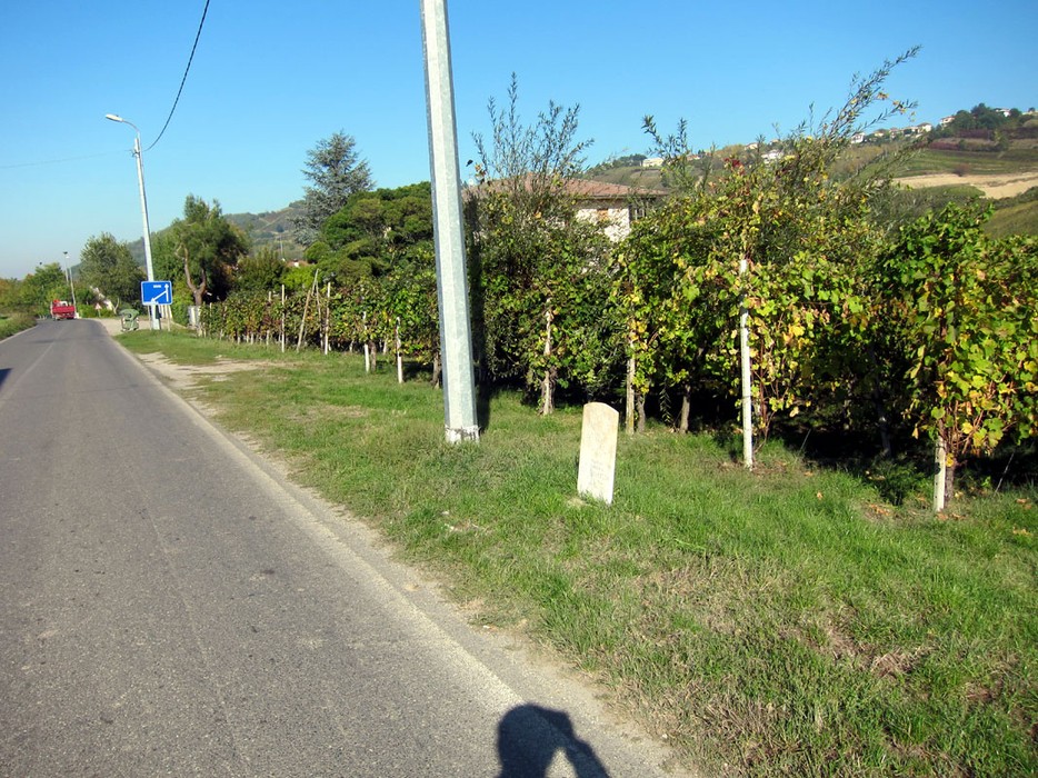 Cippo a Civardi, monumento storico immerso nel verde lungo una strada tra vigne e paesaggio collinare.