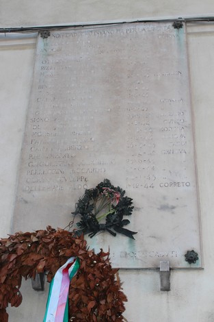 Lapide commemorativa dedicata ai caduti per la Libertà, con corona di fiori e nomi incisi nella pietra.