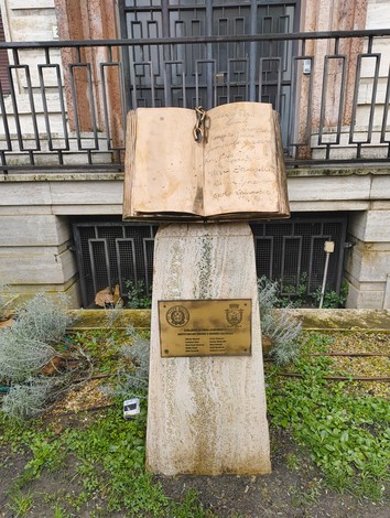 Monumento alle Medaglie al valor militare, con un libro aperto su un basamento commemorativo.